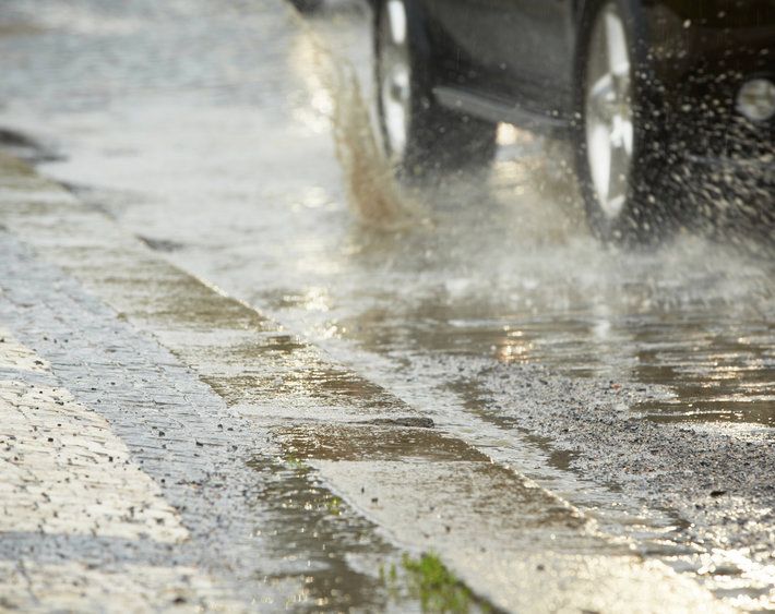 Close up of car tires, driving on road with heavy rain