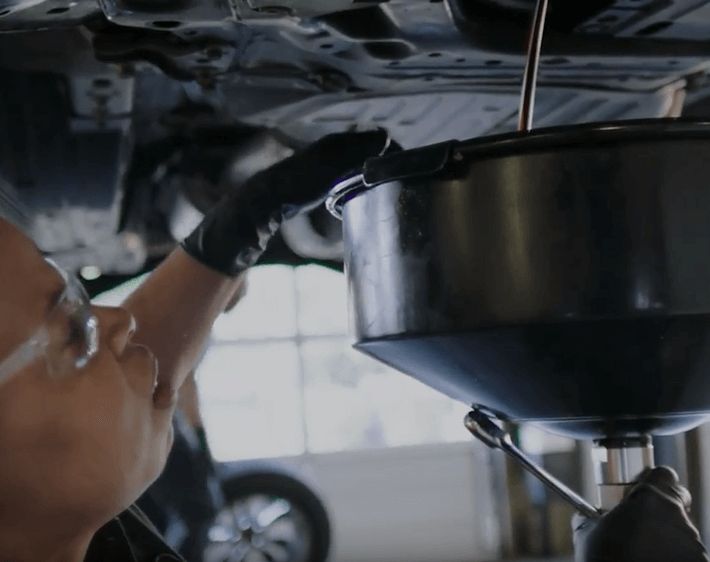 Firestone technician emptying oil from a car to replace with fresh oil