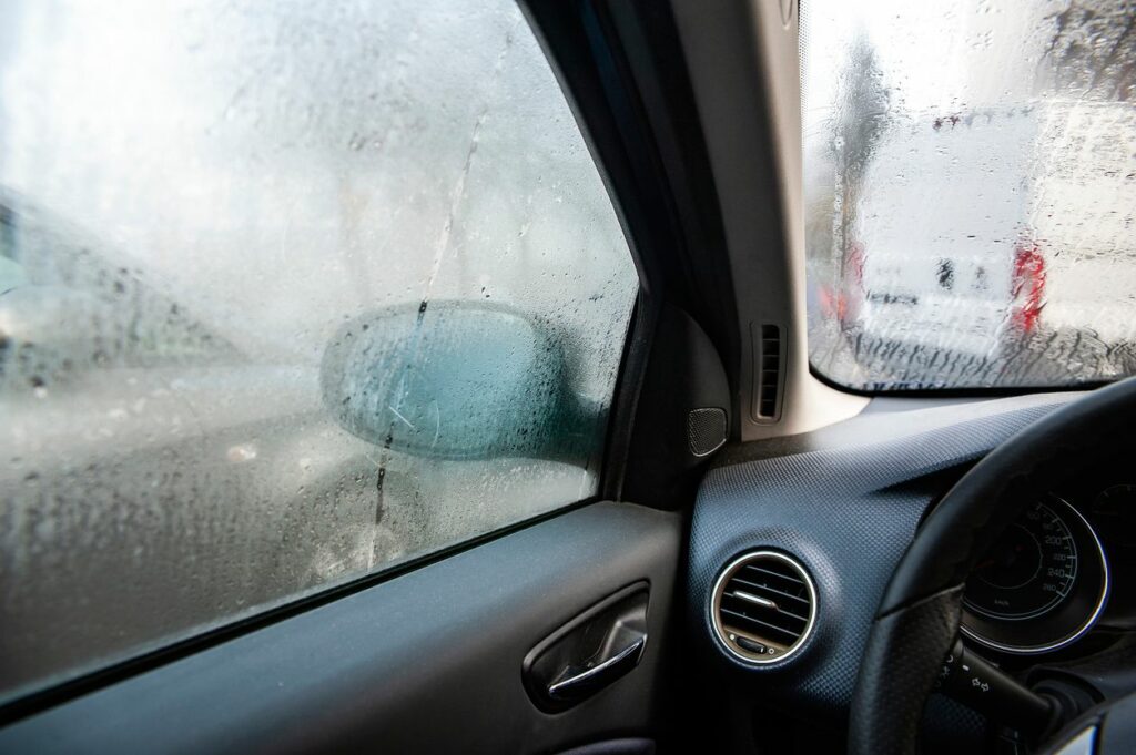 Image from passenger side of vehicle with other cars on the road. Condensation is on the windows.